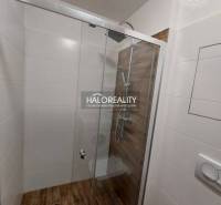 Shower corner in a one-room apartment with modern tiles and a glass screen.