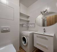 Bathroom in a studio apartment with a washing machine, mirror, and sink.