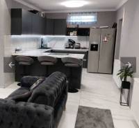A kitchen in a family house with a bar counter, a sofa, and modern equipment.