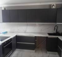 A kitchen in a family house with dark gray cabinets and a marble countertop.
