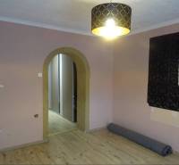There is an empty room in the family house with an arched doorway and a pendant light.