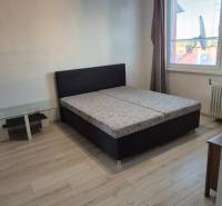 A bedroom in a studio apartment with a double bed and wooden flooring.