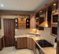 A kitchen of a one-room apartment with a wooden cabinet and built-in appliances.