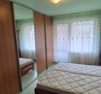 A bedroom in a one-room apartment with a sliding mirror wardrobe and a double bed.