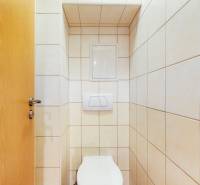 Toilet with tiles in a 2-room apartment, simple white and beige ceramic tiles.