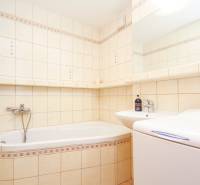 Bathroom with a bathtub, sink, and mirror in a 2-room apartment with tiles.