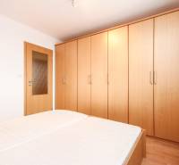 Bedroom with a large wardrobe and light furniture in a 2-room apartment.