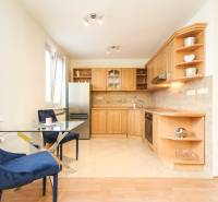 A kitchen in a 2-room apartment with wooden furniture and a dining table with chairs.