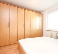 Bedroom in a 2-room apartment with large wooden wardrobes and a window with a radiator.