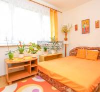 A bright bedroom with an orange bed and houseplants in a 3-room apartment.