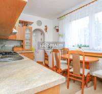 A kitchen in a 3-room apartment with a table and chairs, wooden cabinets, a window with curtains.