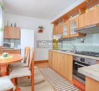 A kitchen in a 3-room apartment with wooden furniture and a dining table with three chairs.