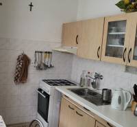 A kitchen in a 3-room apartment with a stove, glass cabinets, and a double sink.