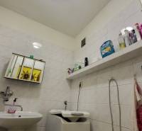 A bathroom in a 3-room apartment with a washing machine, a sink, and storage space for hygiene products.