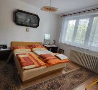 Bedroom in a 3-room apartment with a window, bed, and carpets on the floor.