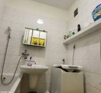 Bathroom with a bathtub, sink, and washing machine in a 3-room apartment.