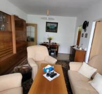 Living room in a 3-room apartment with comfortable seating and wooden cabinets.