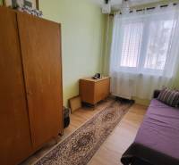 A room in a 3-room apartment with simple furniture, a sofa, and a carpet.