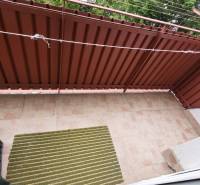 A balcony with tiles and brown railing in a 3-room apartment.