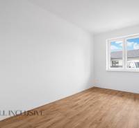 A room in a family house with a wooden floor and a window on the wall.