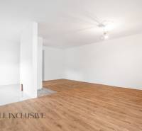 A spacious room with wooden flooring in a family house and white walls.