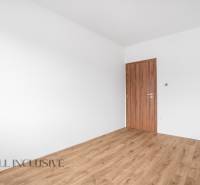 An empty room in a family house with white walls and wooden-colored doors.