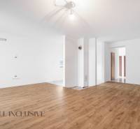 Interior of a family house with wooden flooring, white walls, and an entrance to another room.