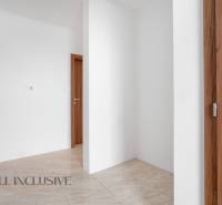 A hallway in a family house with white walls and wooden doors.
