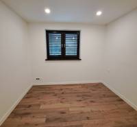 A room in a family house with a wooden floor and a dark window.