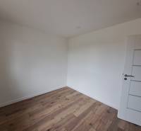 A white empty room in a family house with wooden flooring and white doors.