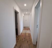 A hallway in a family house with a wooden floor and three rooms.