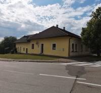 Rodinný dom v Turčianskych Tepliciach v Mošovciach, obklopený cestou a zeleňou pod oblakmi.