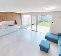 An open kitchen with wooden cabinets and a blue sofa in a family house.
