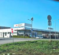 Supermarket Tempo on Repíková street, next to a family house, with a parking lot and cars.