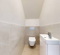 A toilet with a sink in a family house with beige tiles.