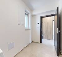 A hallway in a family house with open doors and tiles.