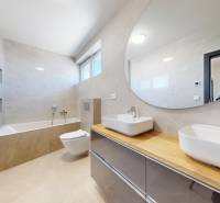 Bathroom in a family house with a bathtub, toilet, and a sink on a wooden countertop.
