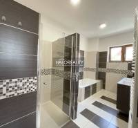 A bathroom in a family house with a bathtub, shower, and sink, decorated with mosaic.