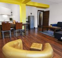 Living room in a two-room apartment with a sofa, kitchenette, and dining table.