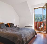 Bedroom with a bed and a balcony in a 2-room apartment with a forest view.