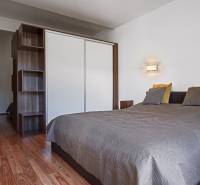 Bedroom with a double bed, wardrobe, and wooden floor in a 2-room apartment.