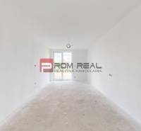 The interior of an empty room in a family house with white walls and doors to the terrace.