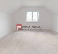 A spacious unused room in a family house with a window and white walls.