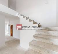 View of the staircase and room in a family house with exposed wall details.