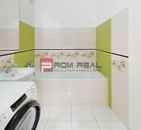 A bathroom with a bathtub, sink, and washing machine in a 2-room apartment.