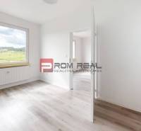 A bright empty room with a window, floor, and white walls in a two-room apartment.