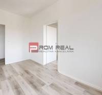 A room with a wooden floor and white walls in a two-room apartment.