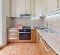 A kitchen in a 2-room apartment with wooden cabinets and a built-in oven.