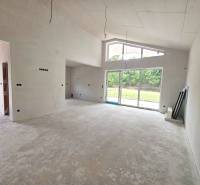A spacious unfinished room in a family house with large windows and a view of the garden.