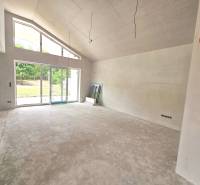 A spacious living room of a family house with large glazing and a view of the garden.